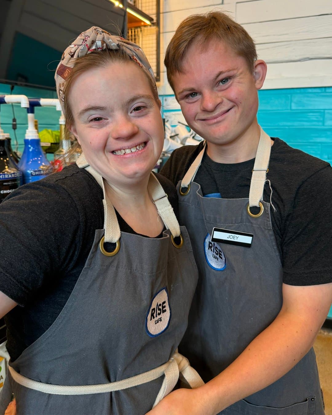 Two people smiling together while working at a coffee counter